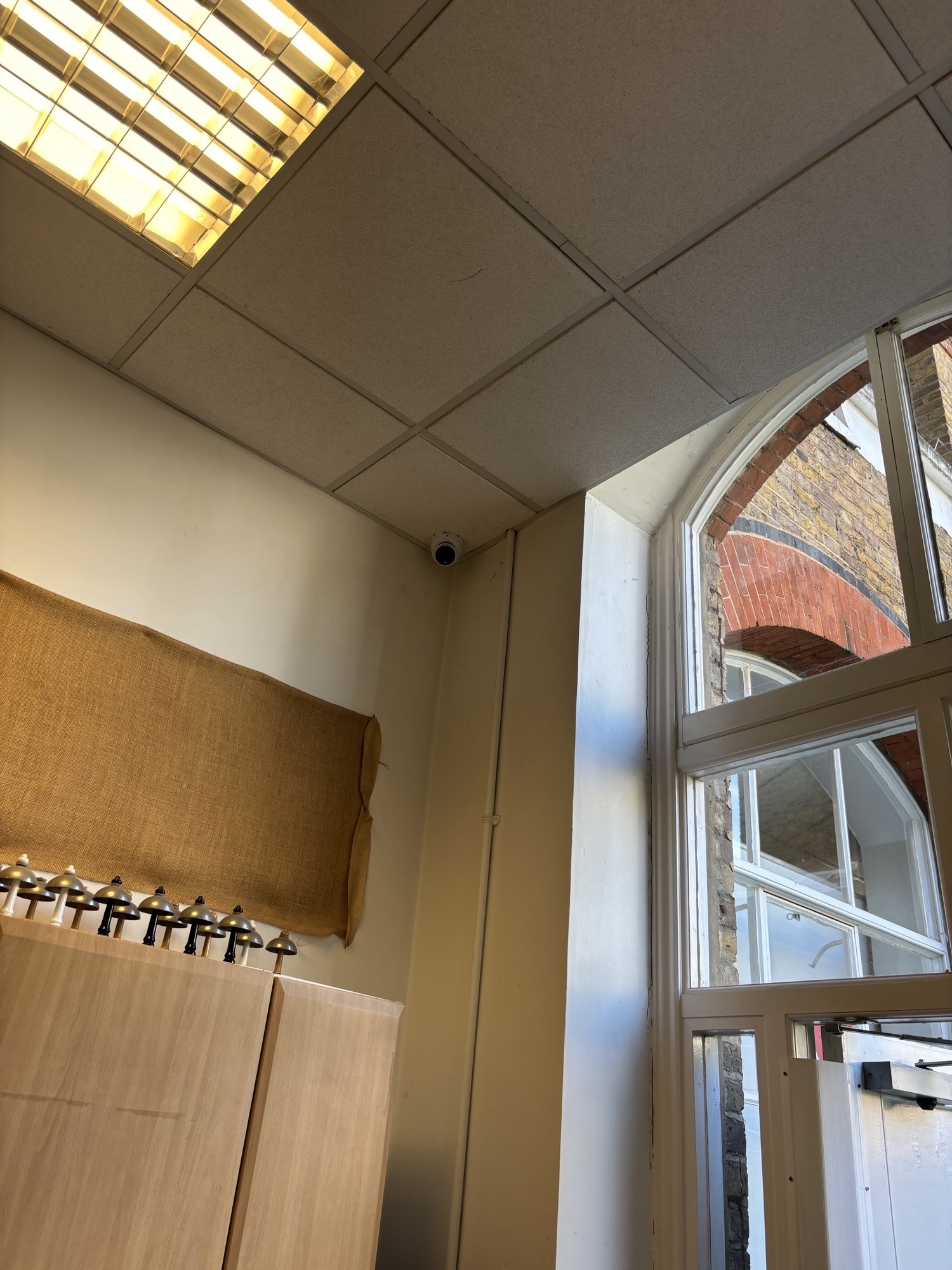 CCTV camera and floodlight mounted on a brick building corner